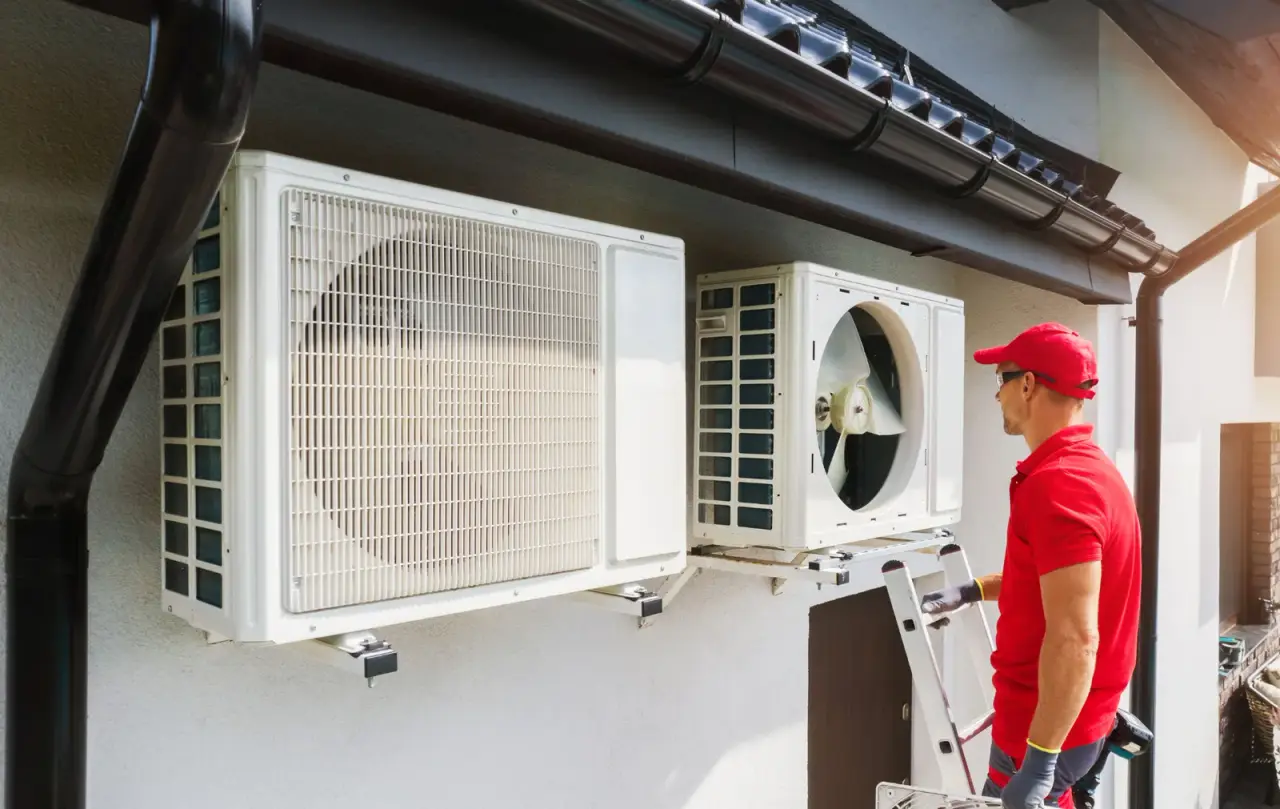 HVAC technician inspecting outdoor AC units mounted on building exterior